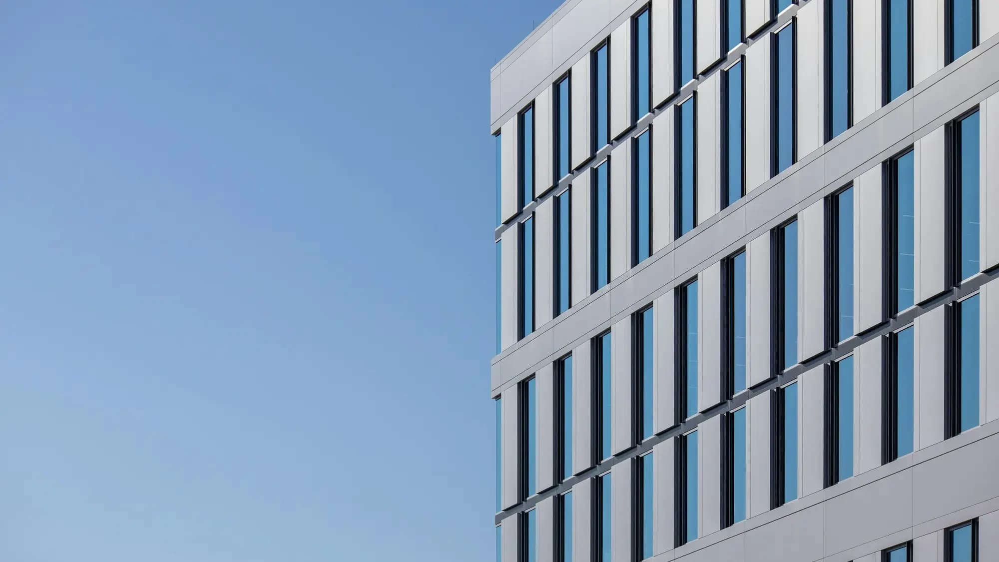 Immeuble blanc aux fenêtres régulières sous un ciel bleu