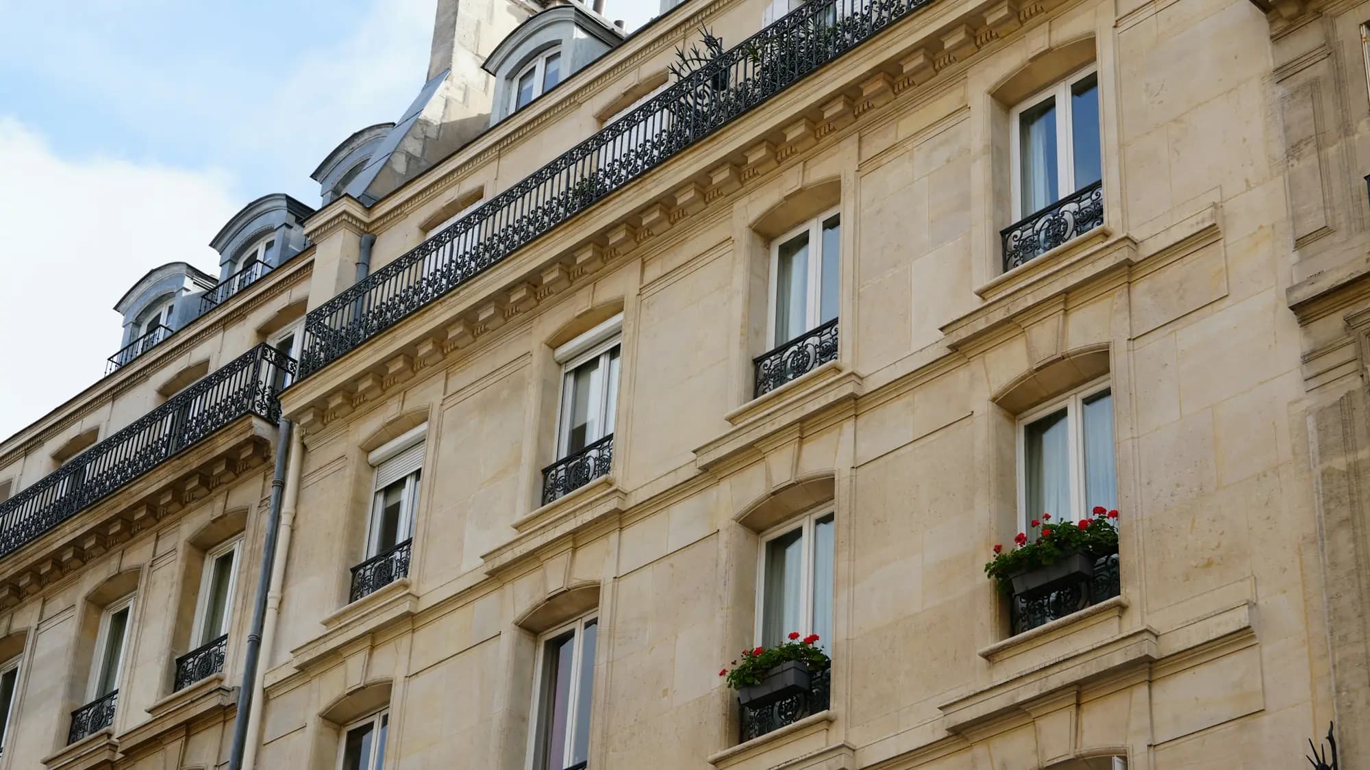 Façade d’immeuble haussmannien en pierre de taille, balcons en fer forgé