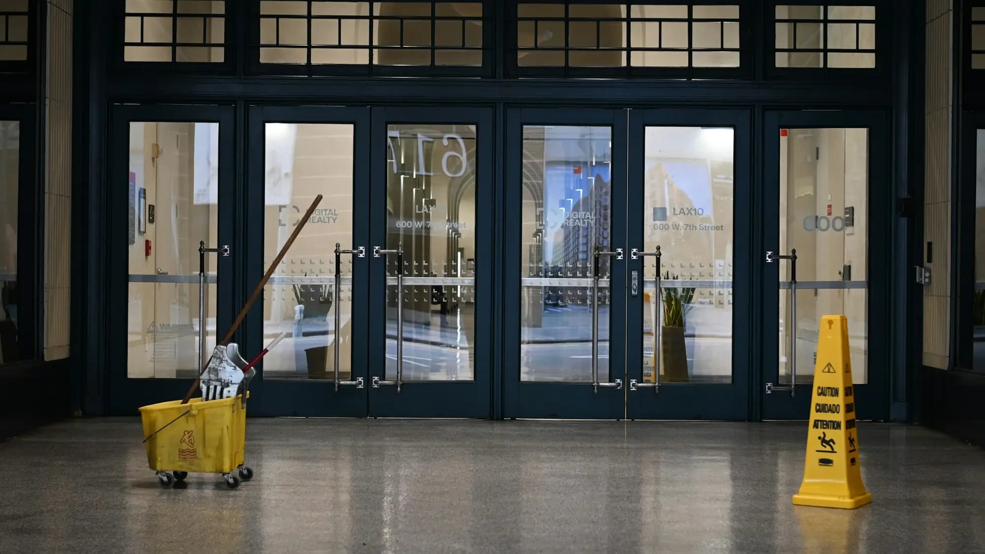 Chariot de lavage et panneau « sol glissant » dans un hall vitré